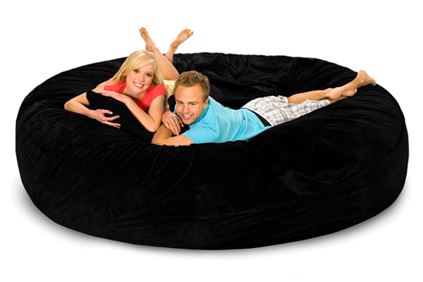 A happy young man and woman relaxing on an 8 ft round black bean bag bed.