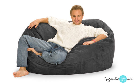 5 ft Gray Oval Bean Bag Lounger with a man sitting on it.
