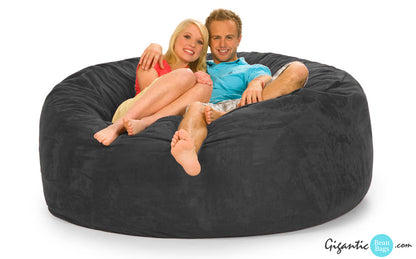 A gray 6 ft bean bag chair with a smiling couple resting on it with  white background. The Gigantic Bean Bags logo is on the bottom right.