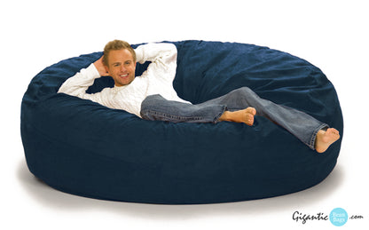 A 7 foot round navy blue bean bag with a man reclining on it with a white background.
