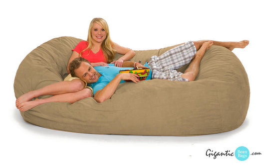 A couple chilling out on a beige bean bag lounger.