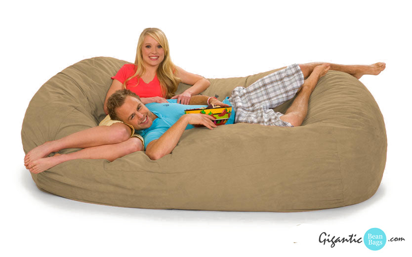 A couple chilling out on a beige bean bag lounger.