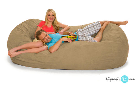 A couple chilling out on a beige bean bag lounger.