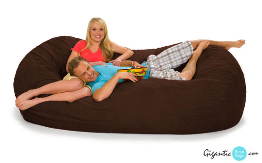A smiling couple relaxing on a 7 and a half foot oval bean bag lounger in Chocolate Brown.