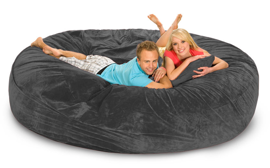 A gigantic 8 ft gray bean bag with 2 smiling people on it.