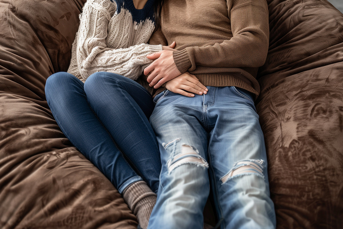 A cozy-looking couple sitting on a big brown bean bag couch.
