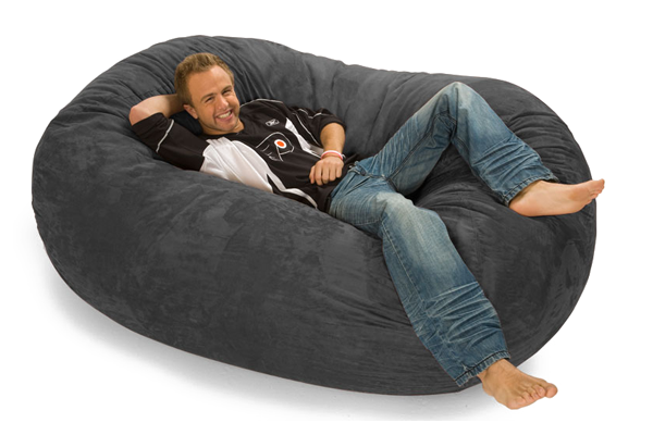 A smiling man relaxing on a gray bean bag lounger
