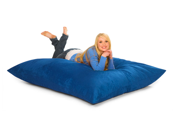Happy girl on a 6 ft bean bag pillow in blue.