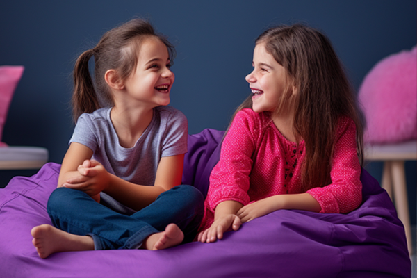 Two kids on a purple bean bag laughing