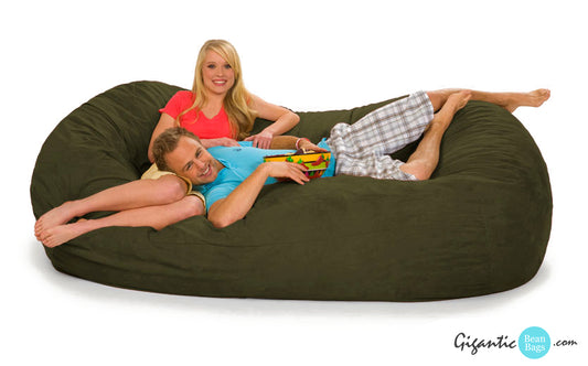 An Italian Olive Green Bean Bag Lounger (Oval). Two people are laying out on it with a bowl of chips.