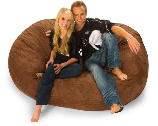 A man and woman sitting on a brown 6 ft. Oval Bean Bag Lounger.