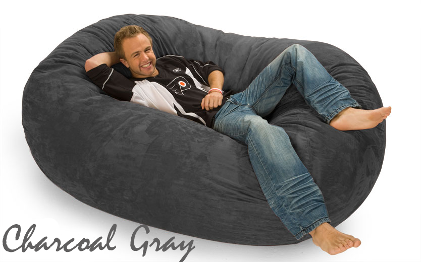 6 ft. Oval Bean Bag Lounger in Charcoal Gray with a guy resting on it. The words "Charcoal Gray"  are written in cursive on the bottom left.